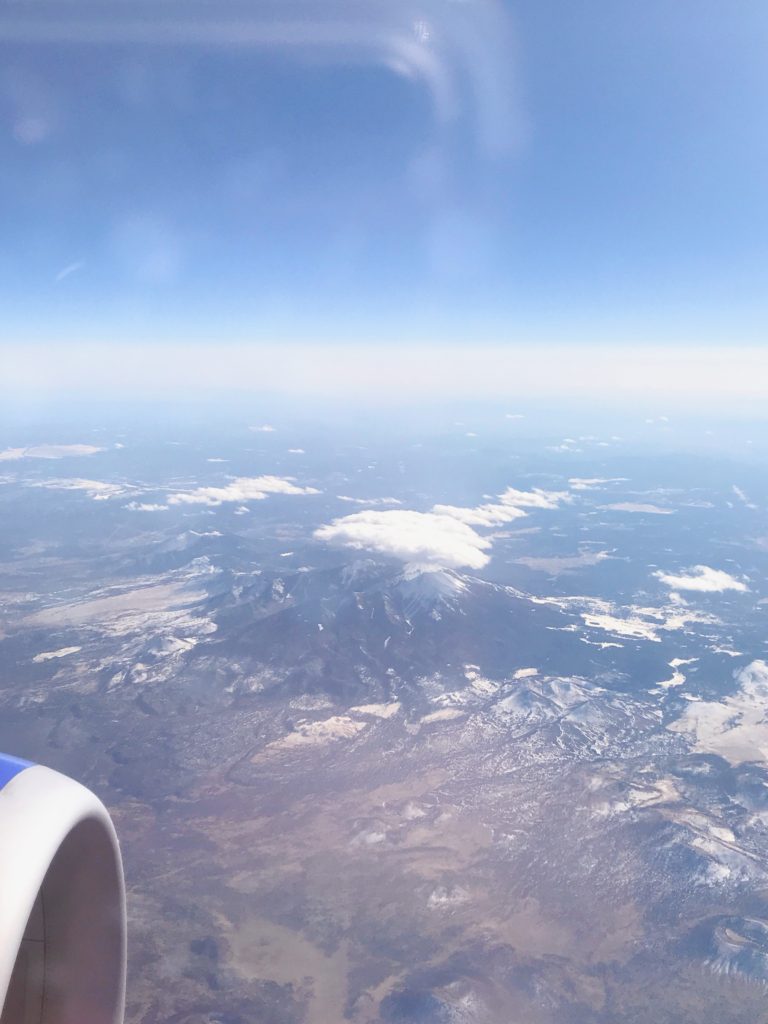 view from the plane, a cloud is hovering over a mountain below
