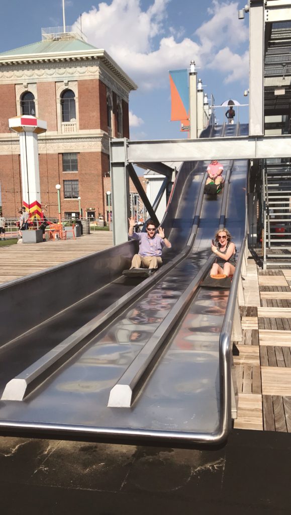 Friends sliding down a long metal slide